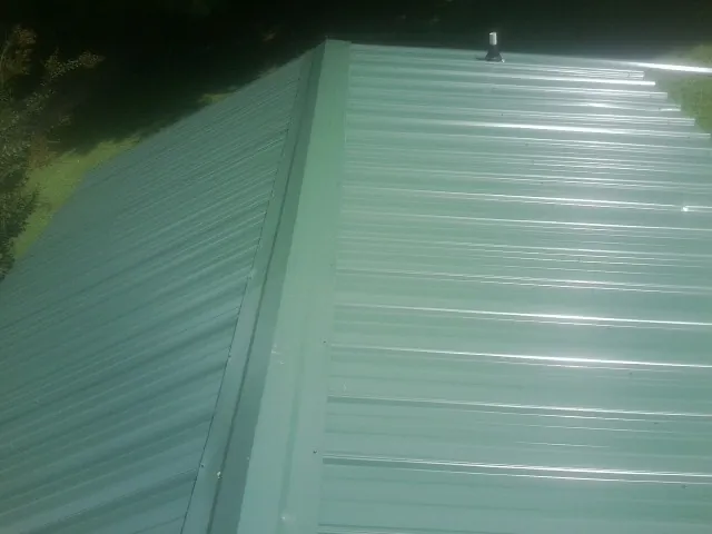 New green metal panels meeting at the ridge of a roof — Flat Roof Repair work by our crew in Buffalo Creek