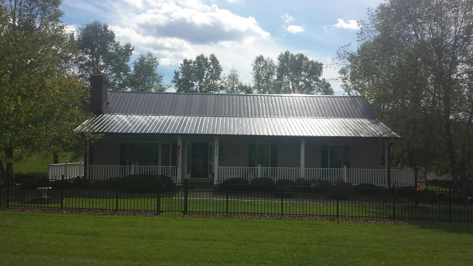Gray metal roof on a brick ranch with a full width front porch — Gutter Guard Installation work by our crew in Buffalo Creek