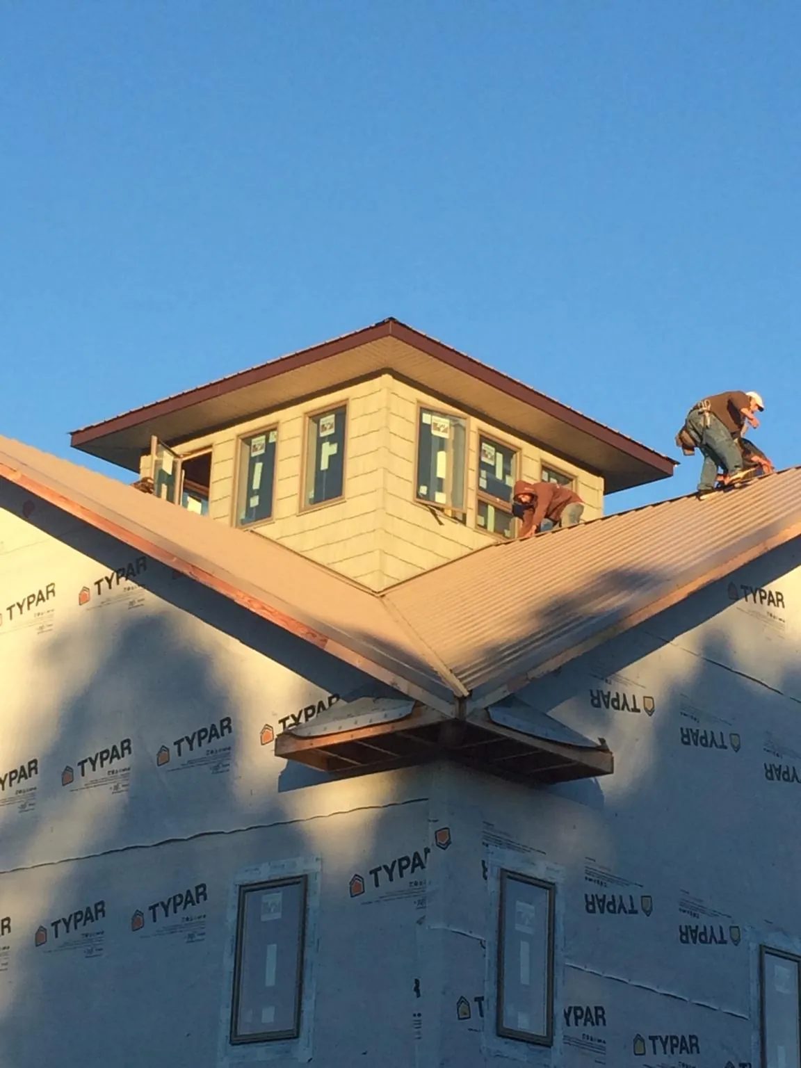Roofers working around a rooftop cupola on a new metal roof at sunset — Roof Waterproofing in Buffalo Creek by Roofing Brothers